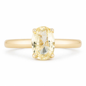Front view of an antique-inspired engagement ring featuring an oval pale yellow sapphire held in a delicate four-claw yellow gold setting.