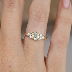 Close-up of the cushion-cut diamond framed by sparkling trefoil diamond shoulders, worn on a finger.