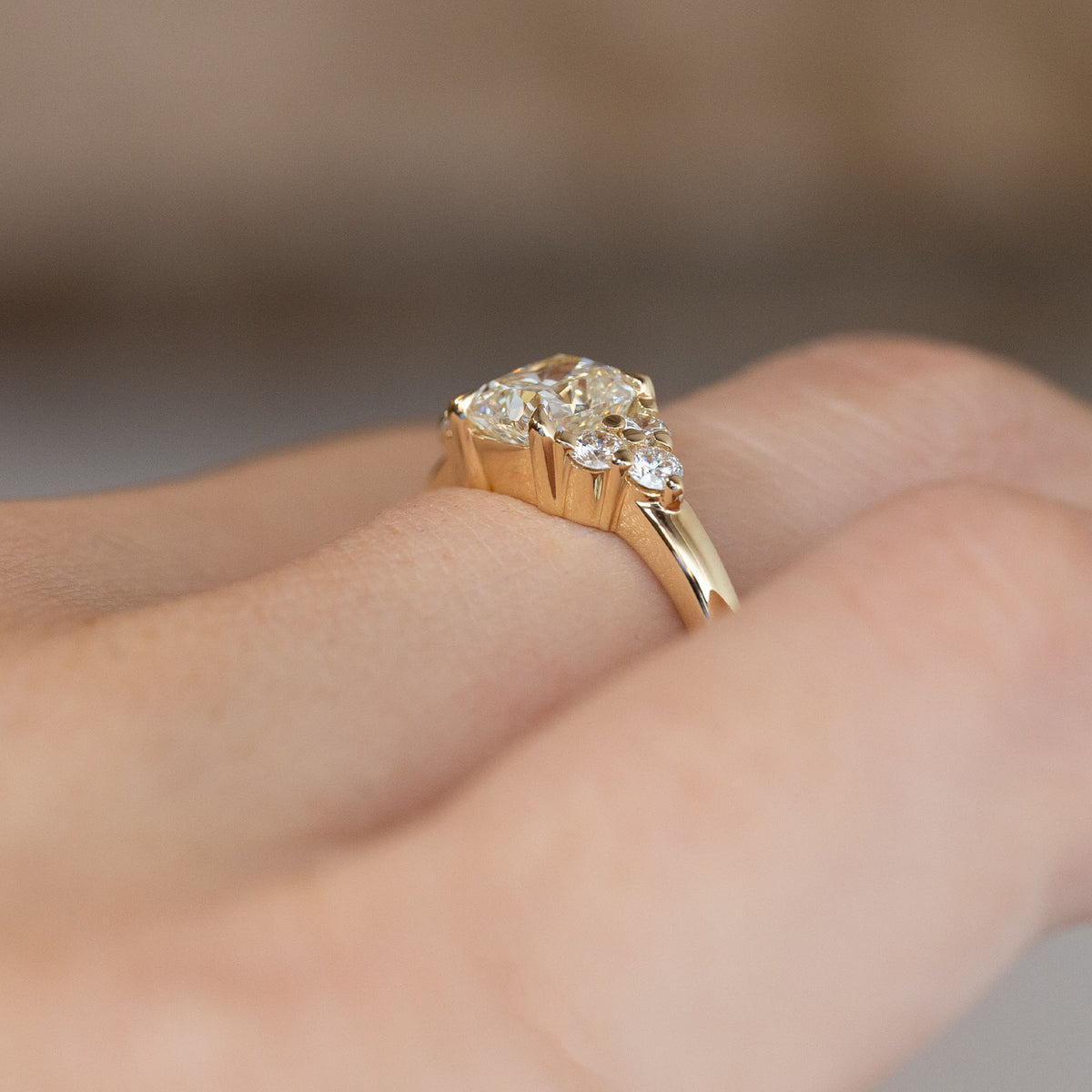 Side-angle view of the diamond engagement ring worn on a hand, highlighting the elevated setting and delicate yellow gold band.