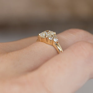 Side-angle view of the diamond engagement ring worn on a hand, highlighting the elevated setting and delicate yellow gold band.