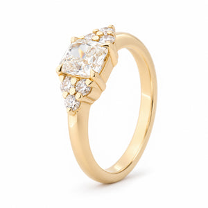 Angled view of the diamond trefoil ring, highlighting the raised claw setting and decorative three-diamond shoulder clusters.