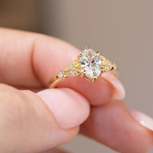 Handheld close-up highlighting the fine beaded gold details and small shoulder diamonds.