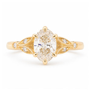 Vintage-inspired pale yellow diamond engagement ring with decorative laurel-leaf trefoil shoulders in yellow gold.