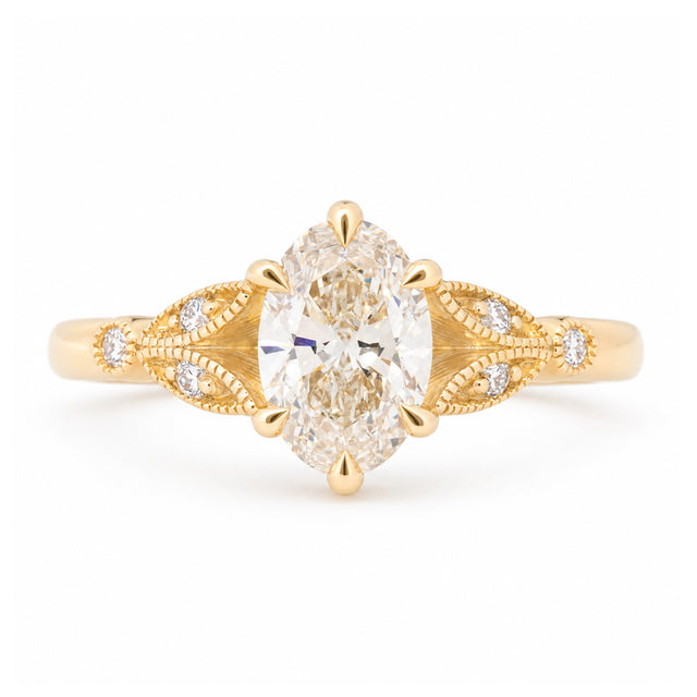 Vintage-inspired pale yellow diamond engagement ring with decorative laurel-leaf trefoil shoulders in yellow gold.