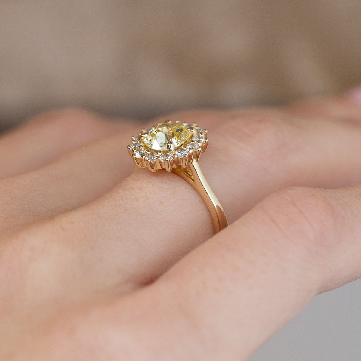 Side-angle view of the diamond cluster ring worn on a hand, highlighting the elevated setting and delicate yellow gold band.