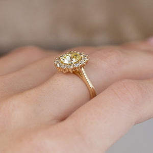 Side-angle view of the diamond cluster ring worn on a hand, highlighting the elevated setting and delicate yellow gold band.