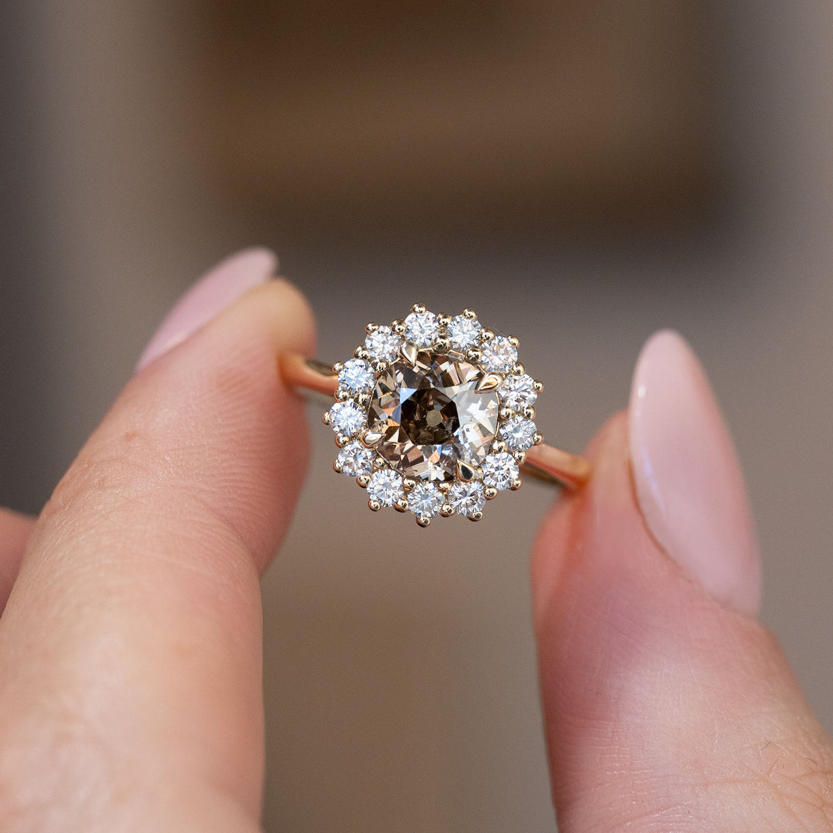 Hand-held close-up of the smoky cognac centre diamond surrounded by brilliant white diamonds in a floral-inspired cluster.