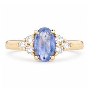 Vintage-inspired blue sapphire and diamond trefoil engagement ring in yellow gold, featuring an oval blue sapphire flanked by sparkling diamond clusters.