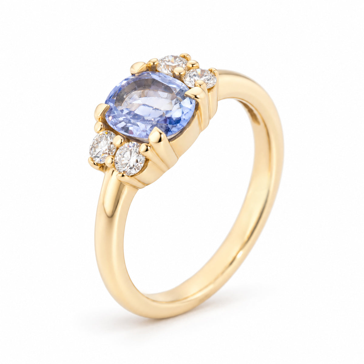 Angled studio view of a vintage-inspired blue sapphire and diamond engagement ring, showcasing its oval gemstone, symmetrical diamond clusters and polished yellow gold band.