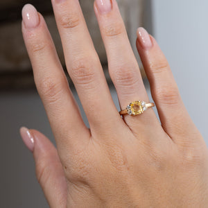 Vintage-inspired yellow sapphire and diamond cluster engagement ring worn on a hand, highlighting the warm golden-yellow gemstone and sparkling diamond accents.