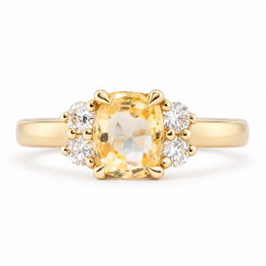 Front view of a vintage-inspired yellow sapphire and diamond cluster engagement ring in yellow gold, featuring a cushion-cut yellow sapphire flanked by four sparkling round diamonds.