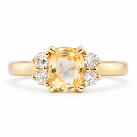 Front view of a vintage-inspired yellow sapphire and diamond cluster engagement ring in yellow gold, featuring a cushion-cut yellow sapphire flanked by four sparkling round diamonds.