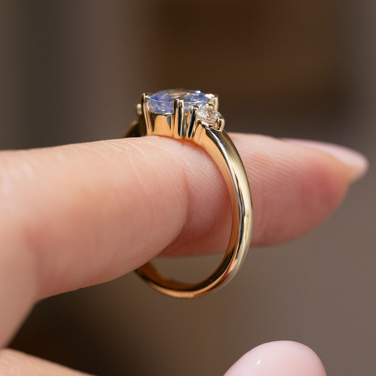 Side profile of the antique-inspired three-stone ring, revealing the claw setting and elegant yellow gold band.