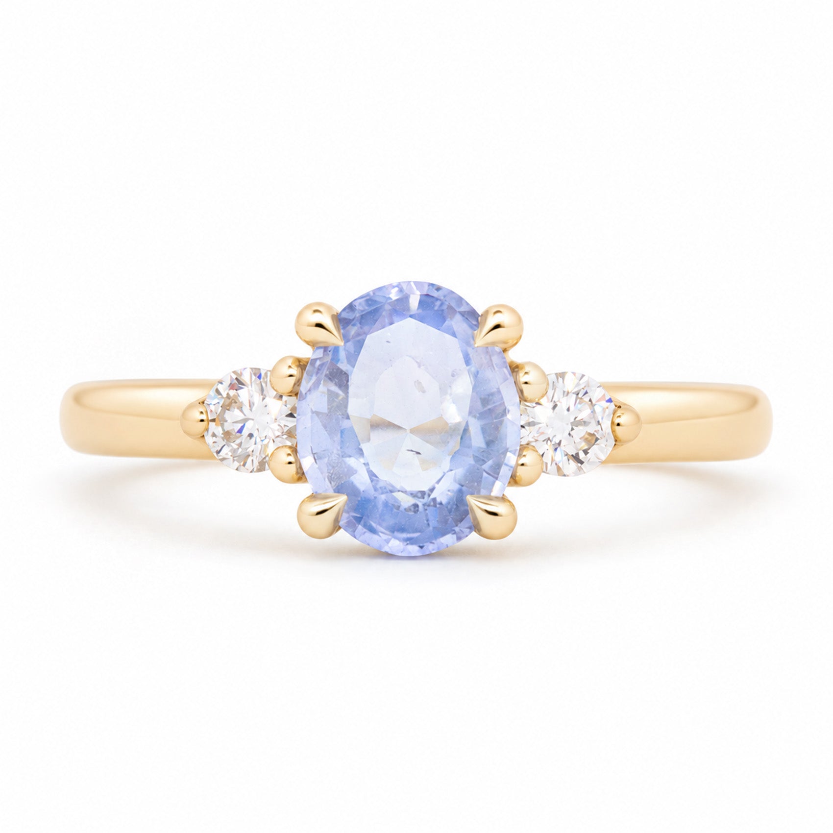 Antique-inspired blue oval sapphire and diamond three-stone engagement ring in yellow gold, featuring two round brilliant-cut diamond shoulders.