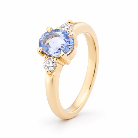 Angled view of the blue sapphire engagement ring, highlighting the raised claw setting and polished yellow gold band.