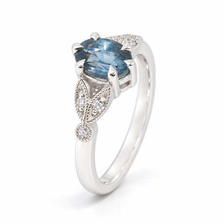 Angled studio view of the sapphire and diamond engagement ring, showcasing its intricate platinum setting, sparkling diamond accents and elegant tapered band.