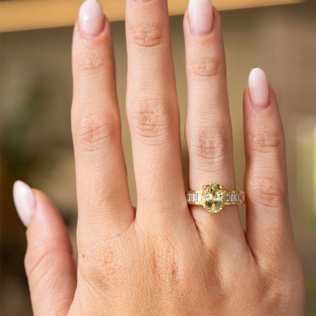 Vintage 1980s green beryl engagement ring worn on the hand, showcasing its oval centre stone and diamond-set shoulders.