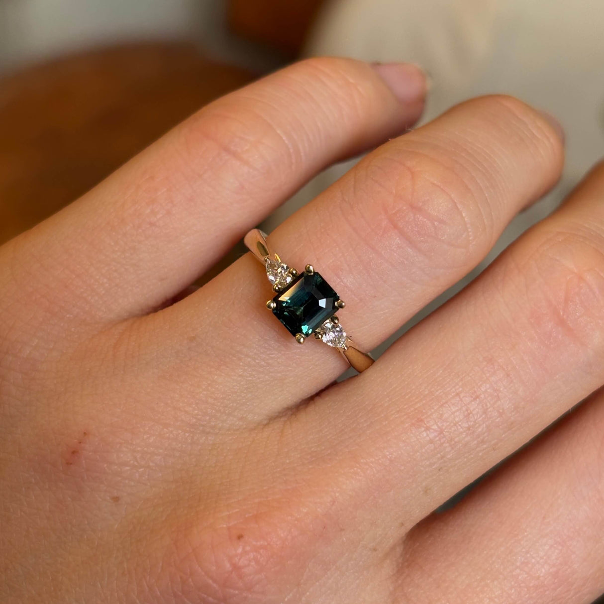 Green sapphire and diamond three-stone engagement ring closeup