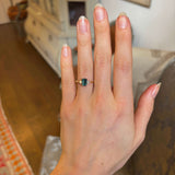 Green sapphire and diamond three-stone engagement ring on hand