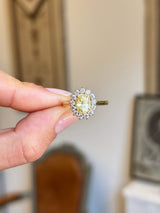 Gold Antique-inspired, yellow sapphire and diamond cluster engagement ring held by a hand against a neutral background