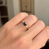 Gold Vintage, 1960s dark blue sapphire & diamond three-stone engagement ring on a person's finger