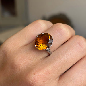 An Antique, Art Deco citrine solitaire cocktail ring on a person's finger