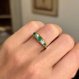 Gold Antique, Victorian emerald & old-mine diamond five-stone engagement ring on a hand against a neutral background