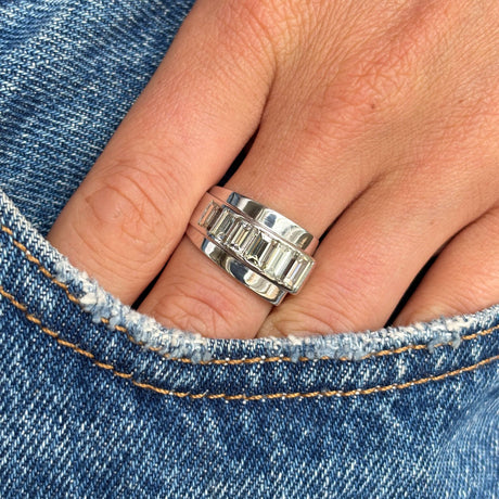 A Vintage, 1940s channel-set baguette-cut diamond ring in platinum worn on a finger with denim background