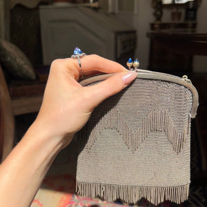 Profile of blue cabochon cut sapphire with an art deco chainmail bag with similar gemstones on clasp