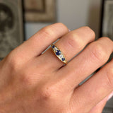 Antique, gold Victorian sapphire & diamond five-stone engagement ring on a hand against a blurred background