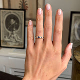Hand wearing a Antique, Victorian sapphire & diamond five-stone engagement ring in yellow gold set against a blurred indoor background.