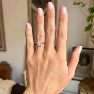 Antique-inspired, princess-cut diamond cluster engagement ring in yellow gold worn on a hand 