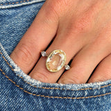 Close-up of a hand wearing a Vintage, 1980s large yellow sapphire & diamond three-stone gold ring on blue denim background