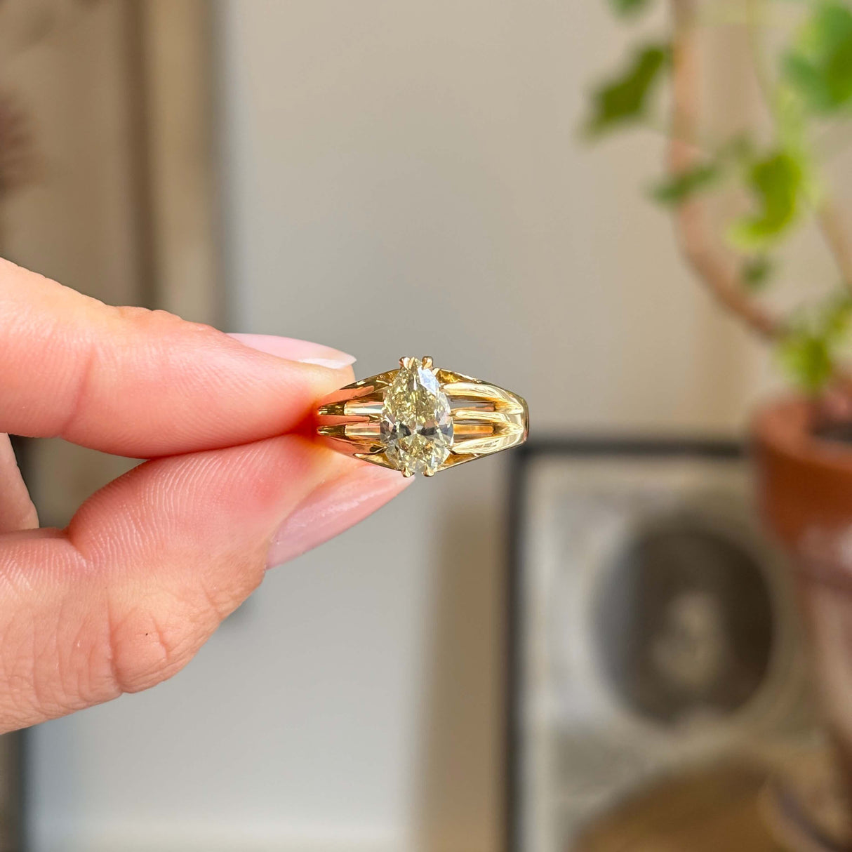 Gold Antique, Edwardian yellow diamond solitaire gypsy ring in yellow gold with a diamond held by a hand against a neutral background