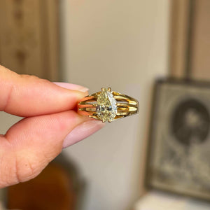 Gold Antique, Edwardian gypsy with a pear-shaped diamond held by a hand against a neutral background