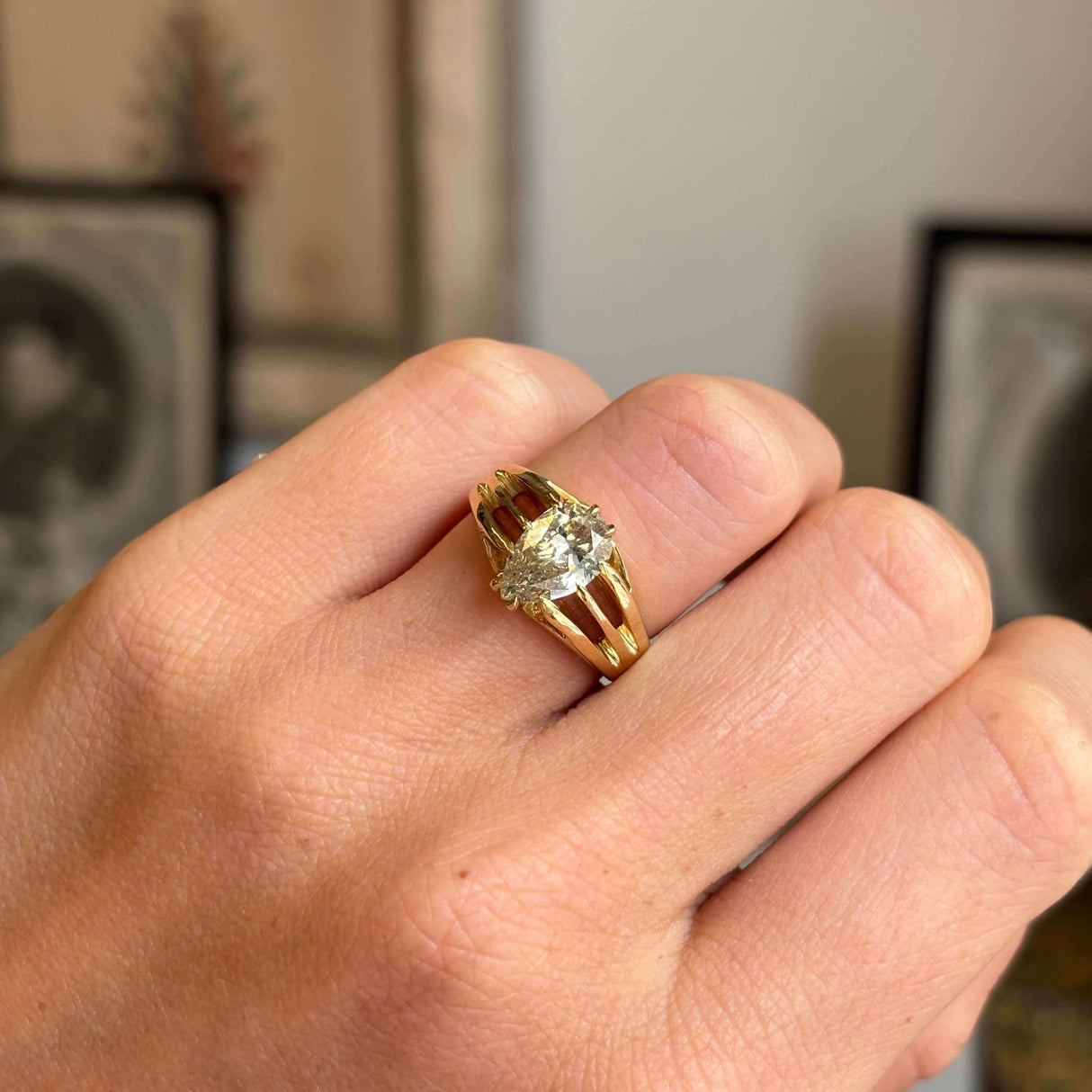 Gold Antique, Edwardian yellow diamond gypsy ring on a person's finger against a blurred background