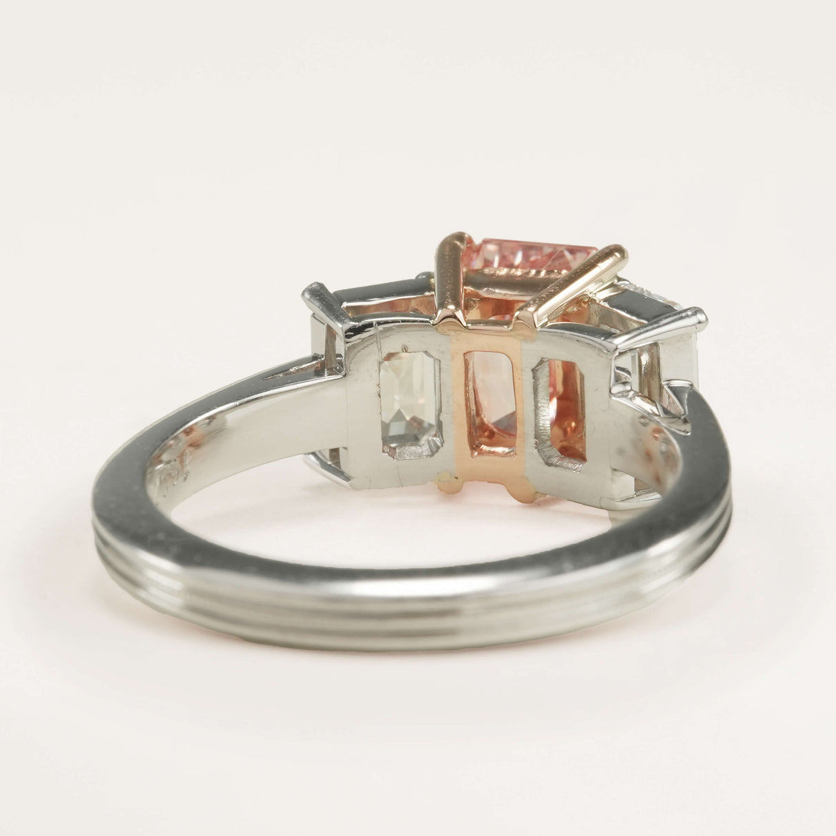 Reverse of the lab-pink diamond and white diamond three-stone ring showing metalwork details and inside the band.