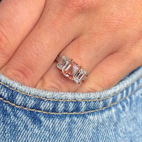 Lab-pink diamond and white diamond three-stone ring being worn on hand, with the hand inside a jean pocket to show scale and everyday wear.