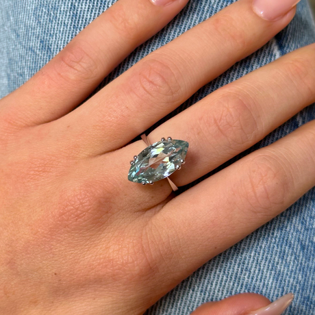 vintage marquise cut aquamarine ring, worn on hand and placed on denim jeans,  front view. 