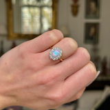 Edwardian opal and diamond cluster ring worn on  closed hand. 