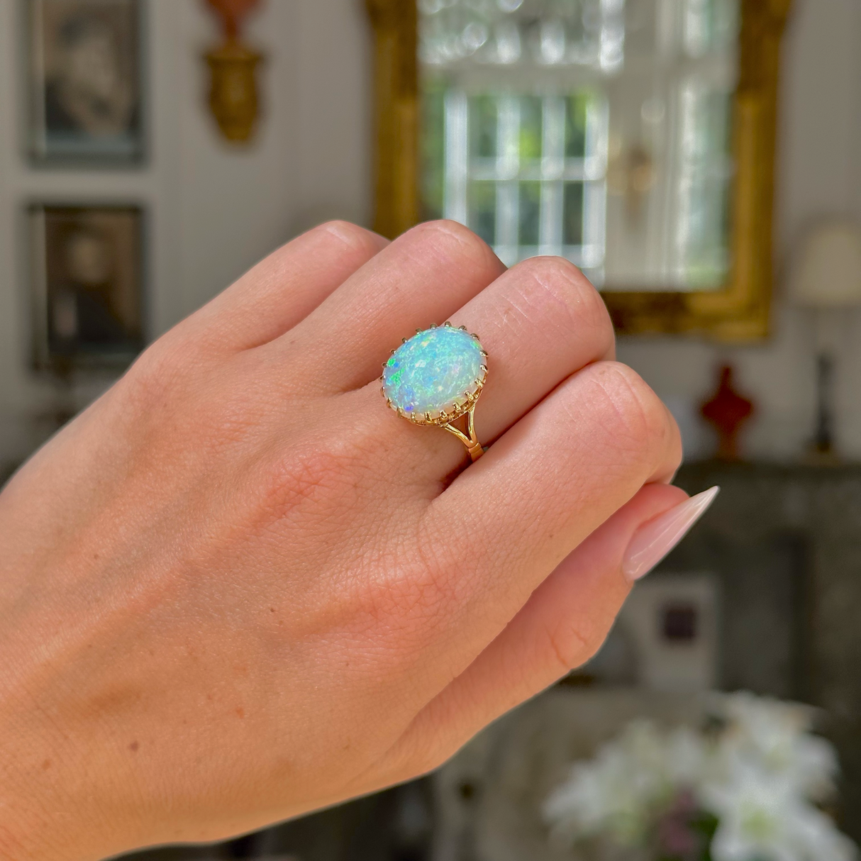 cabochon white opal cocktail ring with 18ct yellow gold band, worn on closed hand, front view. 