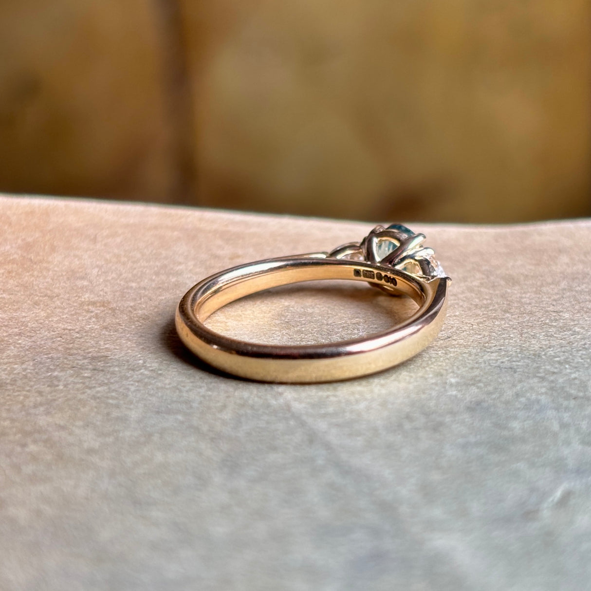 Hallmarks of teal sapphire and diamond three-stone engagement ring.