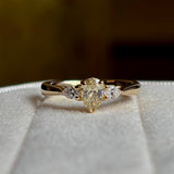 Pear-cut diamond three-stone engagement ring on a blurred background showing details. 