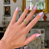 Edwardian peridot and diamond cluster ring, worn on hand.