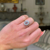 Peach pink sapphire diamond cluster ring worn on closed hand. 
