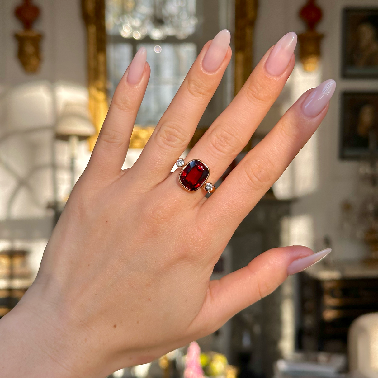 Vintage red zircon and diamond three stone ring worn on hand. 