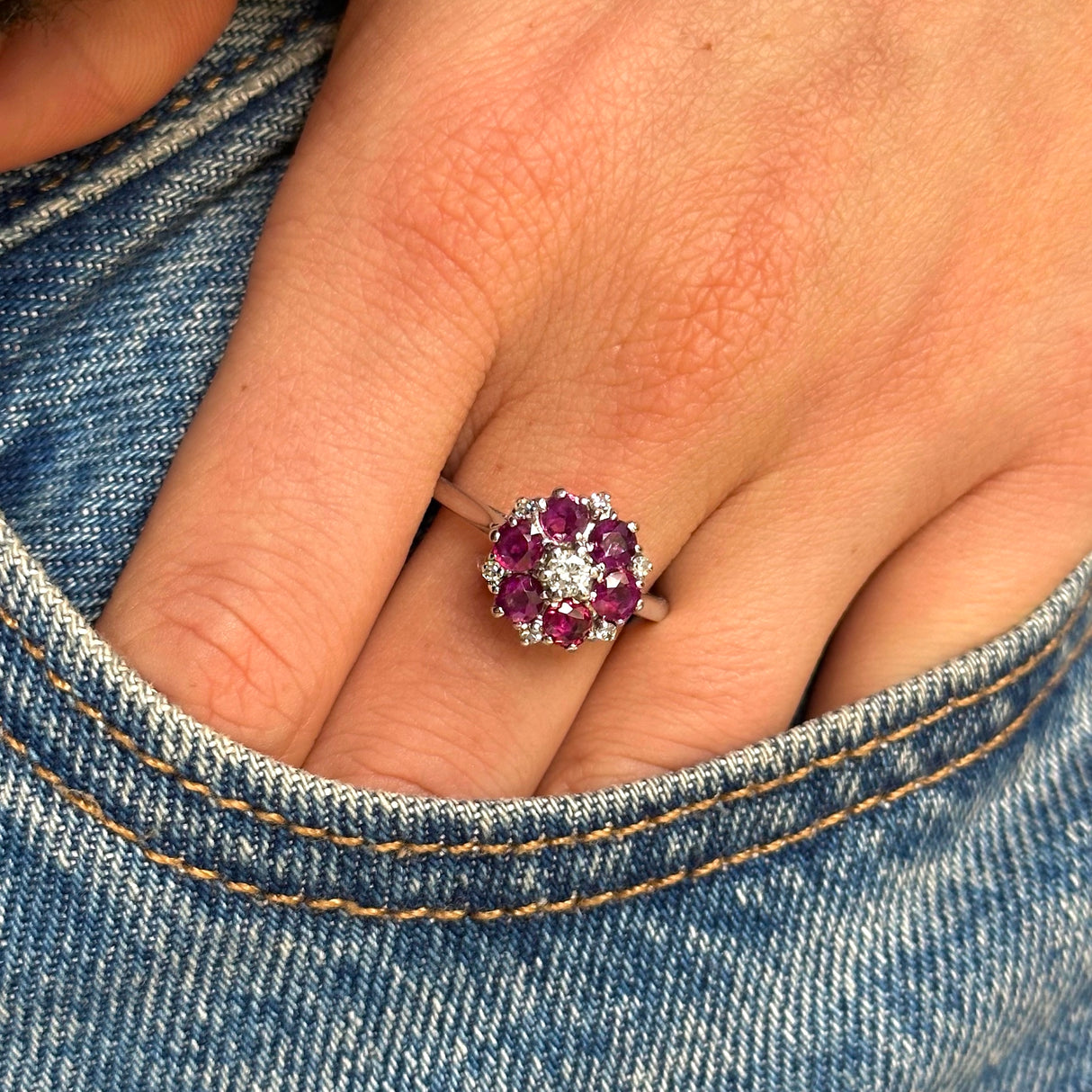 ruby and diamond cluster ring worn hand in placed in pocket of jeans front view. 