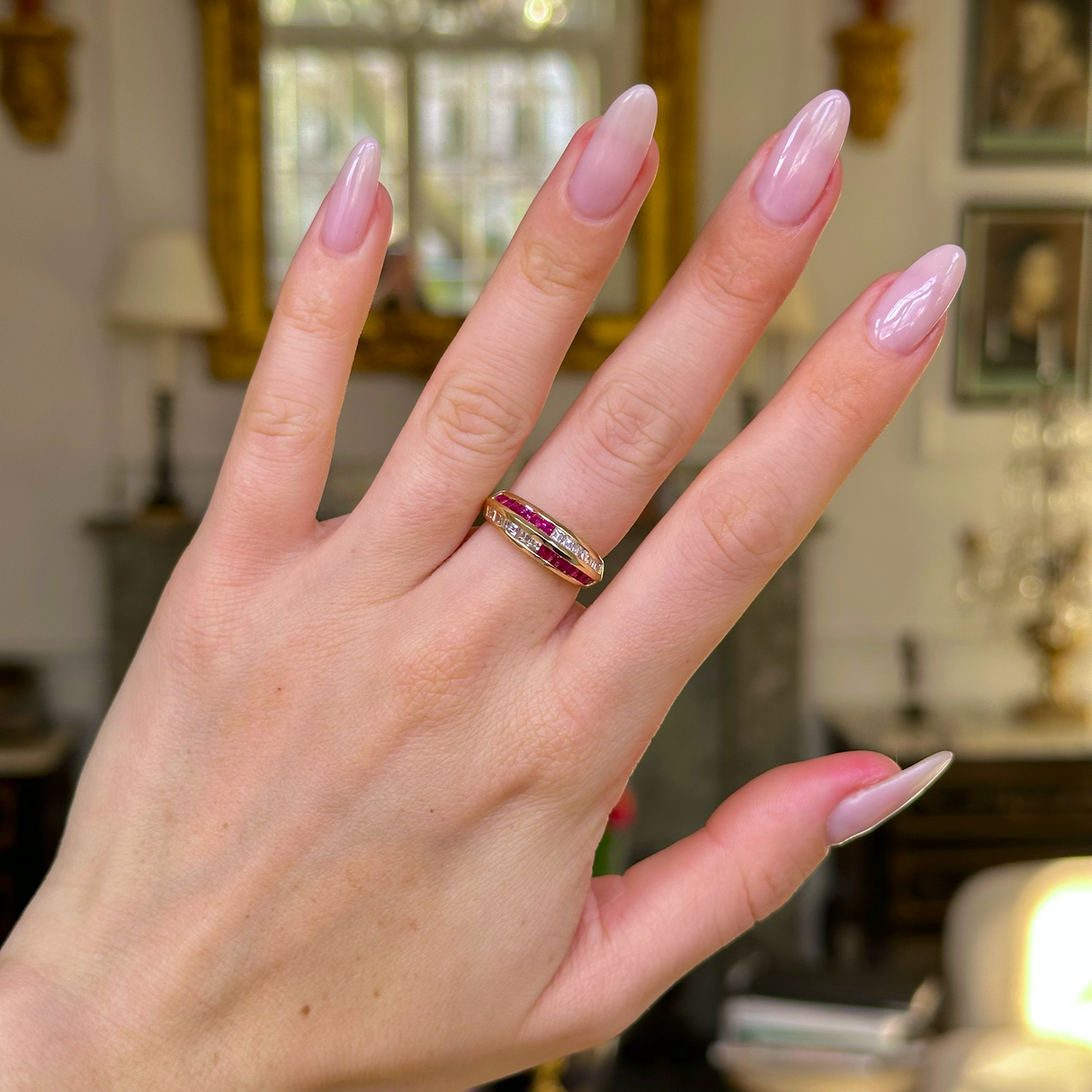 Ruby and diamond half eternity ring worn on hand. 