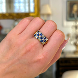 Sapphire and diamond checkerboard ring worn on closed hand.