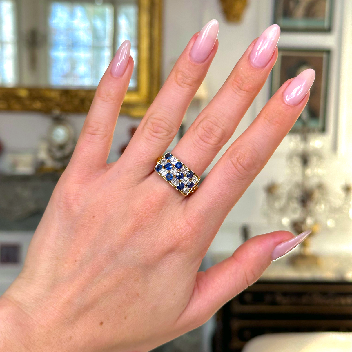 Sapphire and diamond checkerboard ring worn on hand.